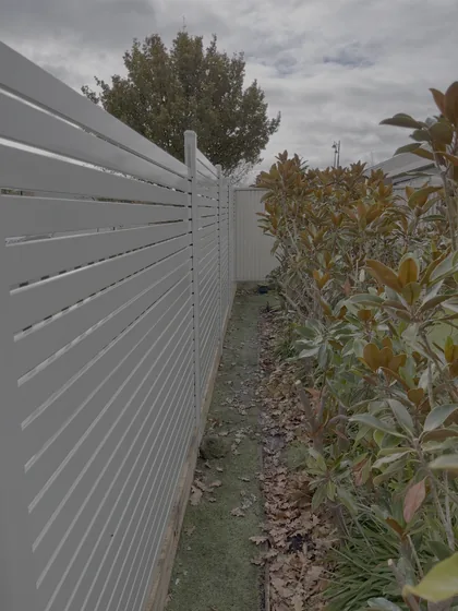 White aluminium horizontal slat privacy screen fence along a side path
